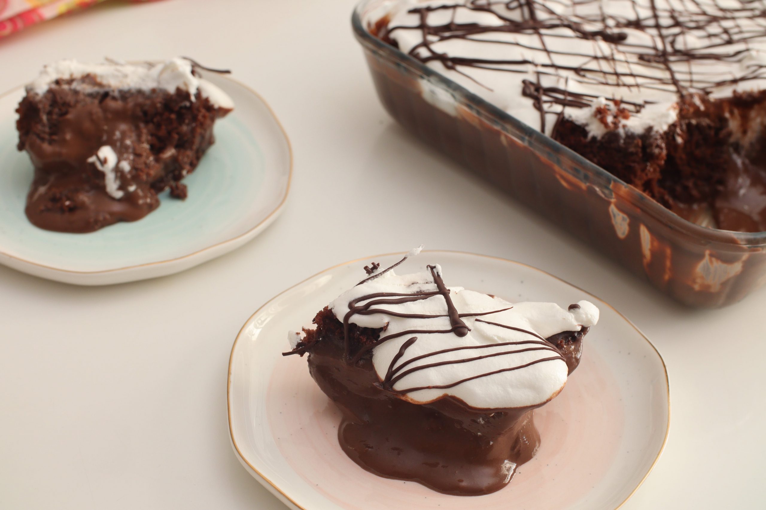 A serving of Chocolate Trifle on a plate with the main trifle dish in the background