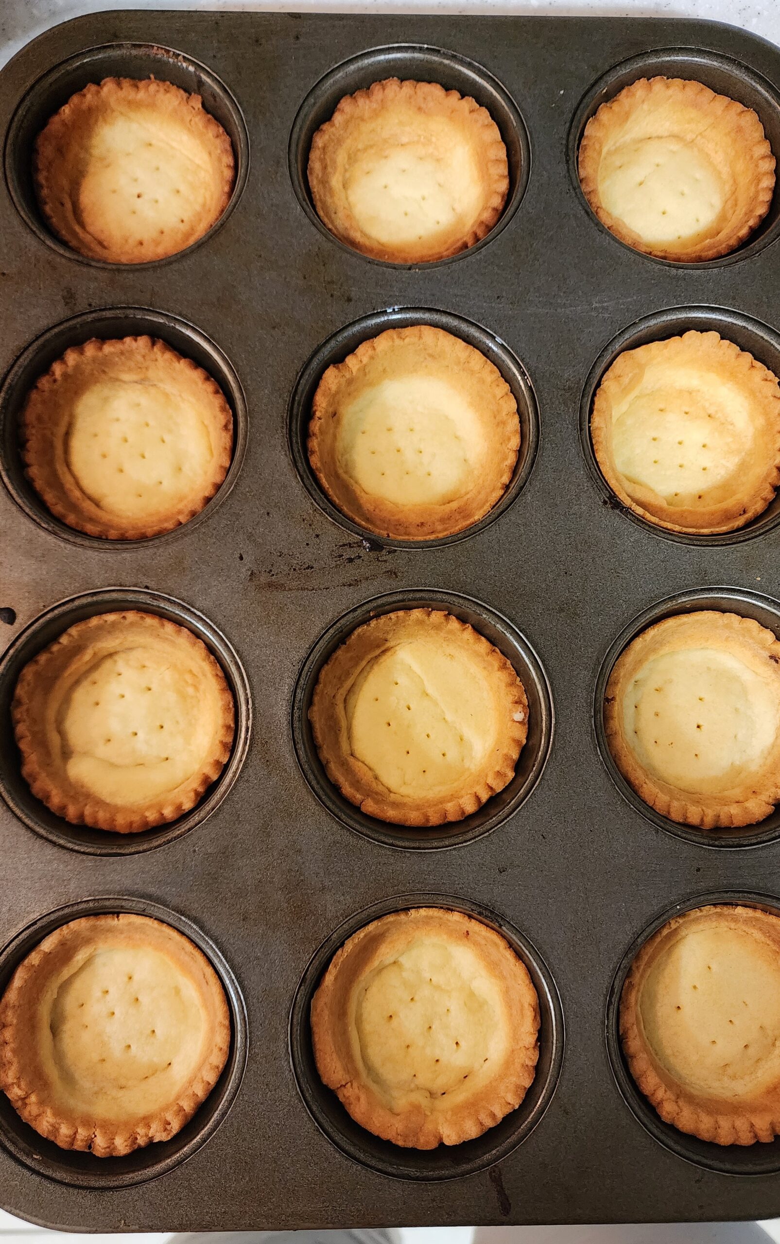 Baked tart shells placed inside a muffin tray