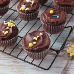 Chocolate Fudge Cupcakes with colorful sprinkles, placed on a wire rack on a rustic background