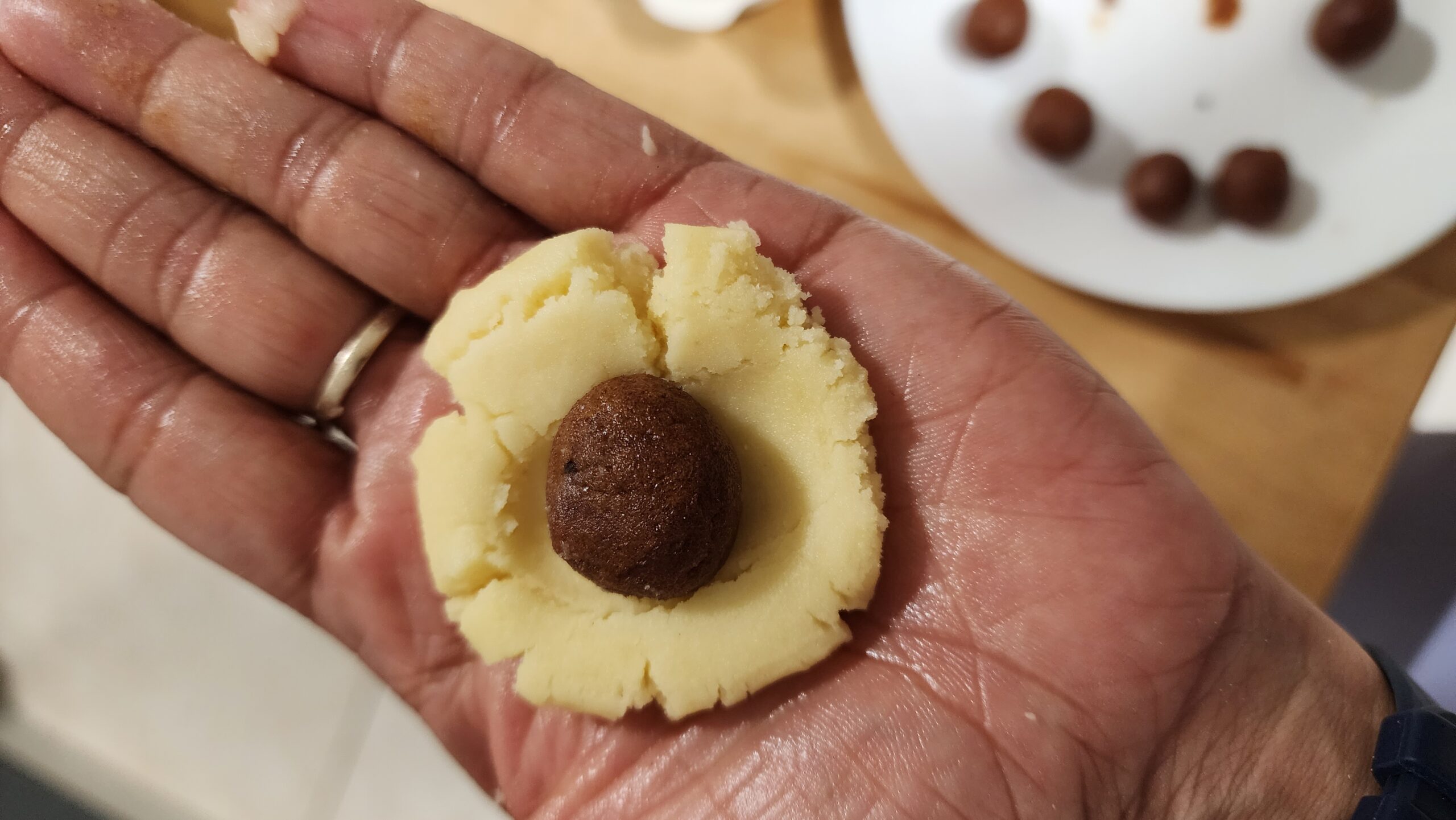 A flattened dough bowl with a date ball placed on a palm
