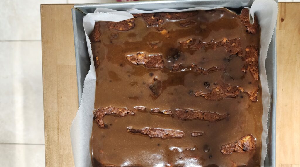 Sticky Date Cake topped with butterscotch sauce in the baking pan