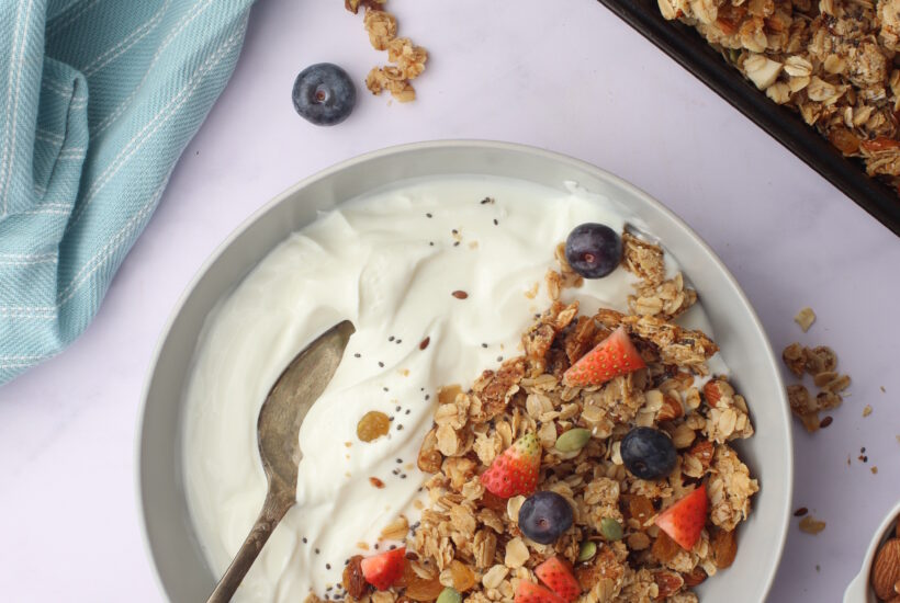 Crunchy granola clusters topped with berries on a side of greek yogurt