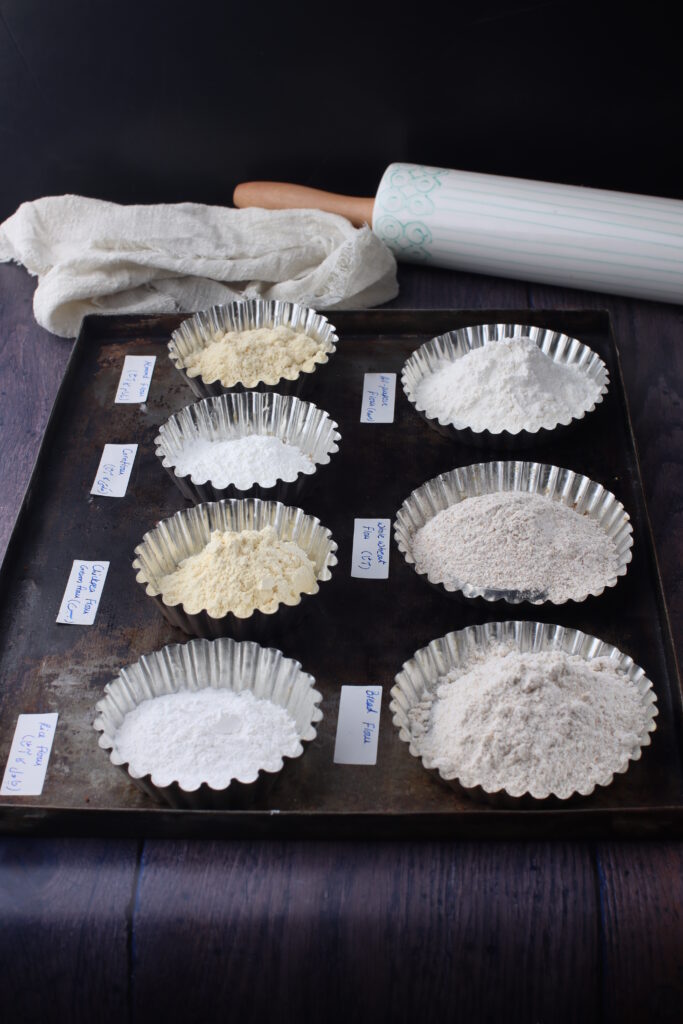 7 different types of floured displayed in small tart pans and labelled with a rolling-pin at the back