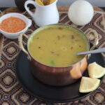 Red lentil soup in a copper bowl, served with lemon wedges