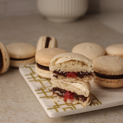swiss macarons, one is in half and filling of ganache and jam showing